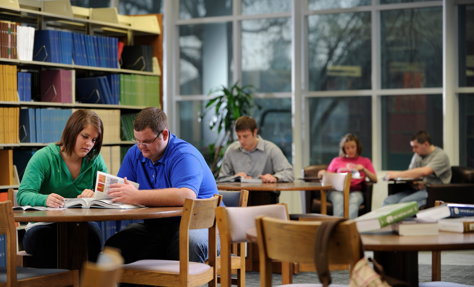 Five students reading to themselves in a library